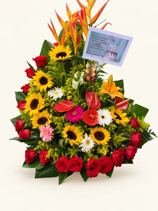 Arreglo de girasoles y rosas rojas con heliconias, anturios, gerberas, lirio y follaje. Sobre fondo crema.