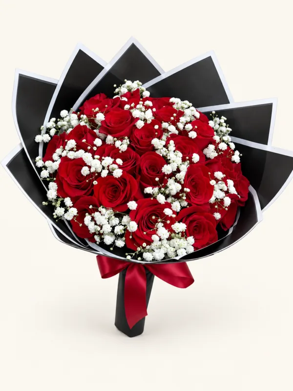 Buqué de rosas rojas con gypsophila blanca, envoltura negra de borde blanco y lazo rojo. Sobre fondo crema.
