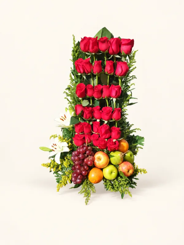 Arreglo vertical de rosas rojas con lirios blancos, frutas y follaje decorativo. Sobre fondo crema. en Pereira