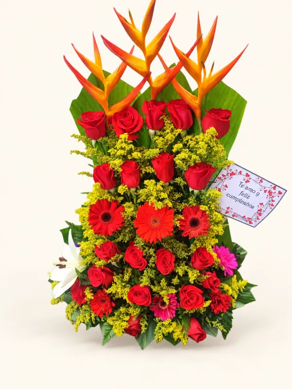 Arreglo vertical con heliconias, rosas rojas, gerberas y flores de acompañamiento. Sobre fondo crema. en Pereira
