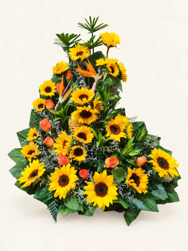 Arreglo de girasoles y rosas salmón con flores tropicales y follaje verde. Sobre fondo crema. en Pereira