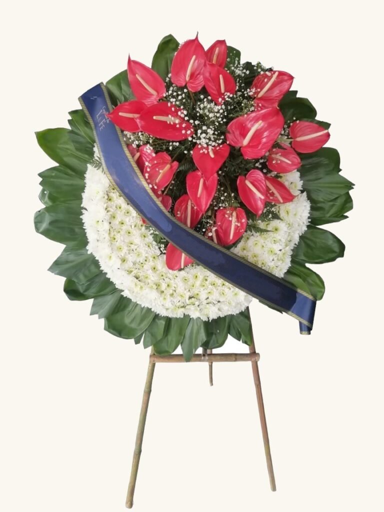 Corona fúnebre de anturios rojos con cinta azul para condolencias en Pereira